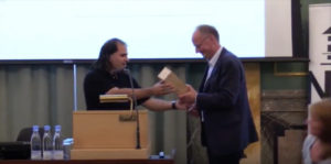 Nima Arkani-Hamed handing over a $150 bottle of cognac to Poul Damgaard.